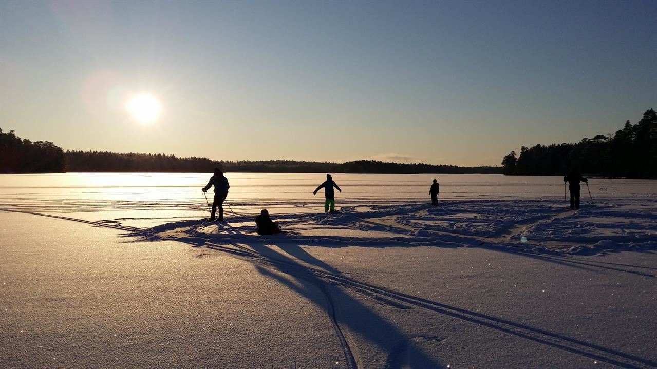 Familj som leker på i isen i vinterlandskap.