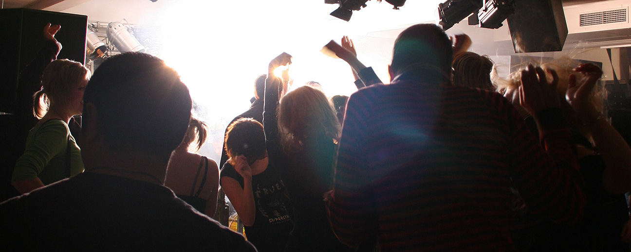 En publik dansar framför strålkastare.