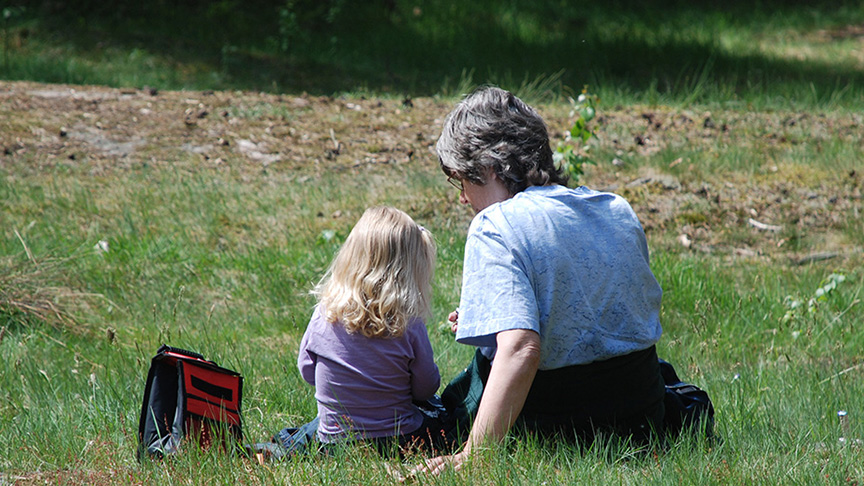 En kvinna och ett barn sitter i gräset.
