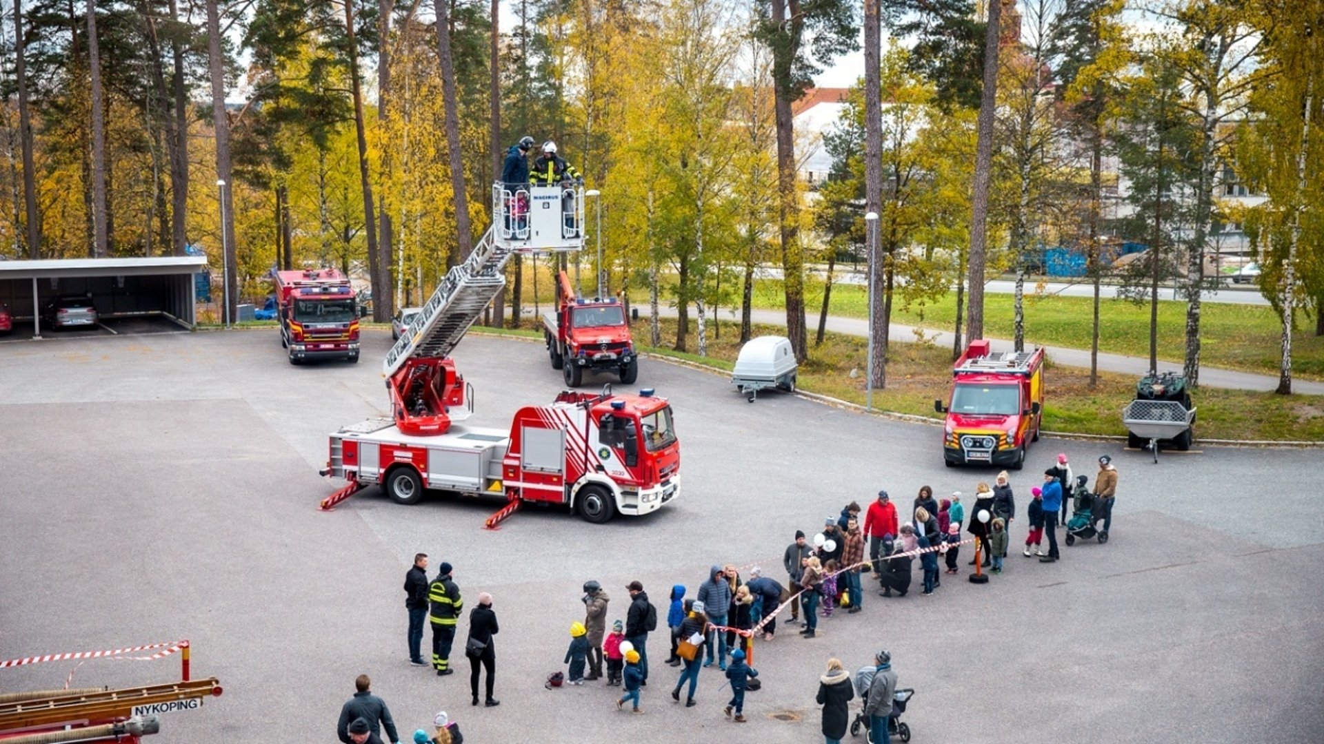 Flera räddningsfordon uppställda utanför Nyköpings brandstation och åskådare som tittar.