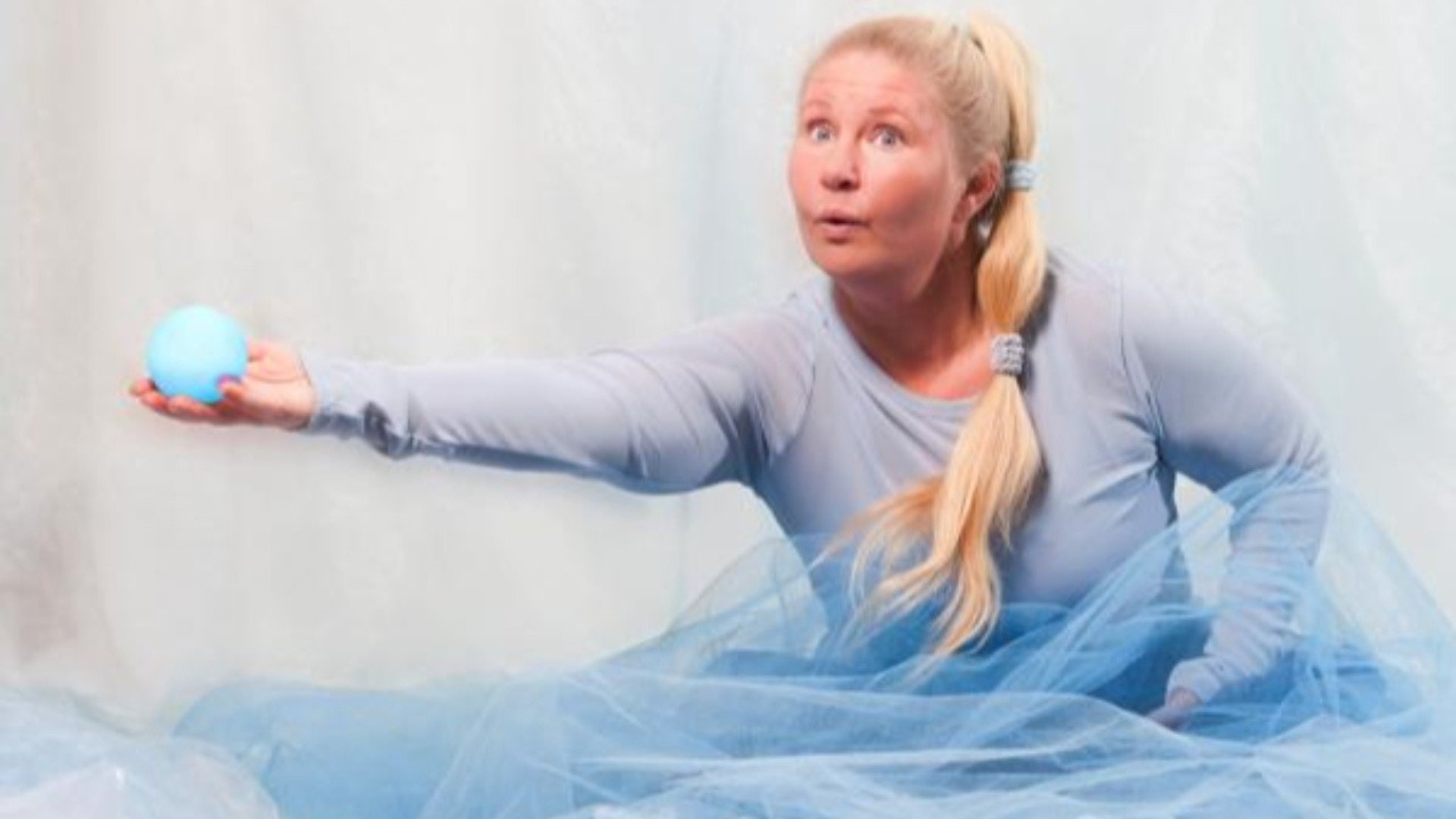 En kvinna i blått sträcker ut handen. I handen håller hon ett blått lysande klot.