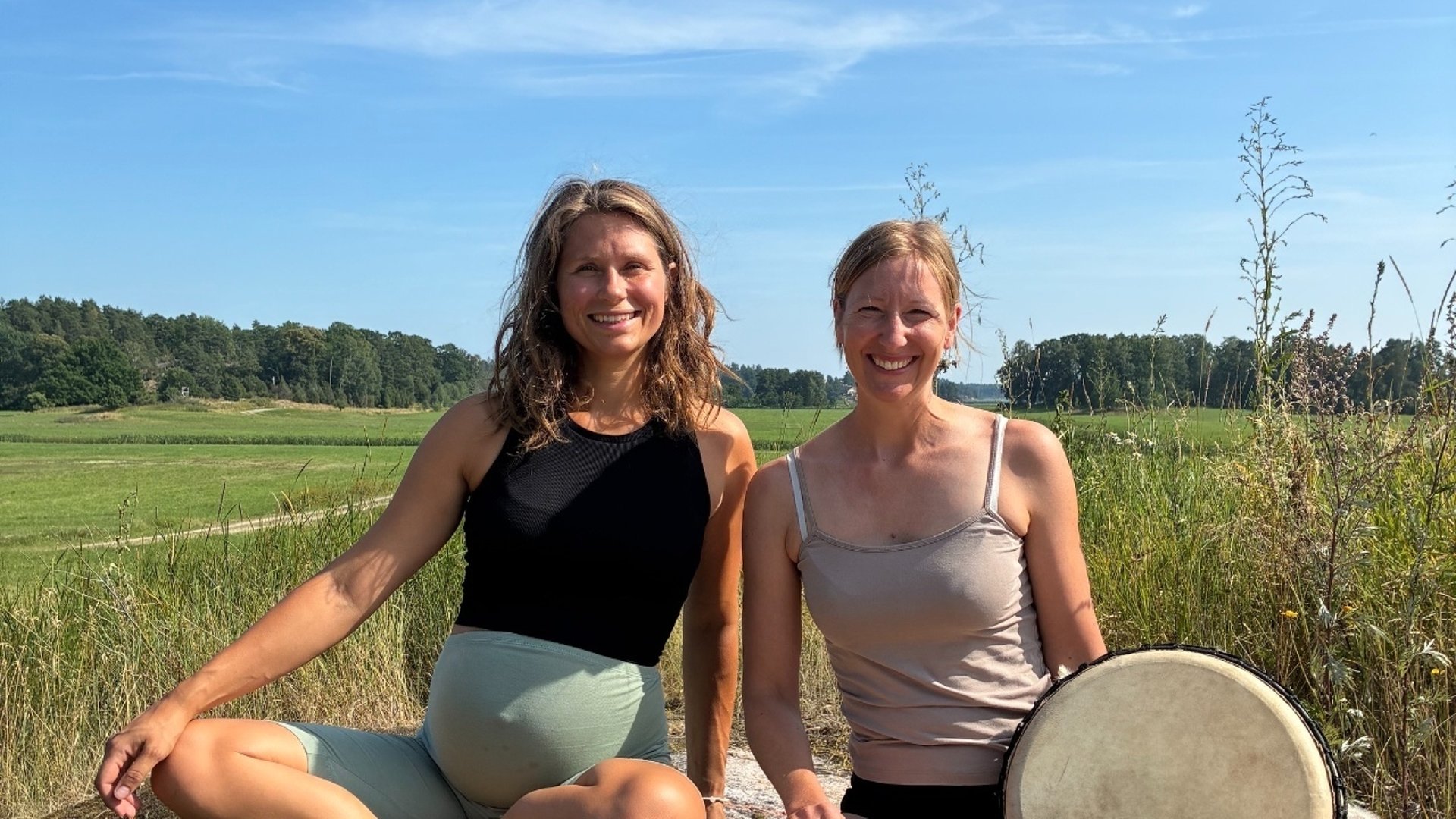 Två kvinnor som sitter i en acker natur.