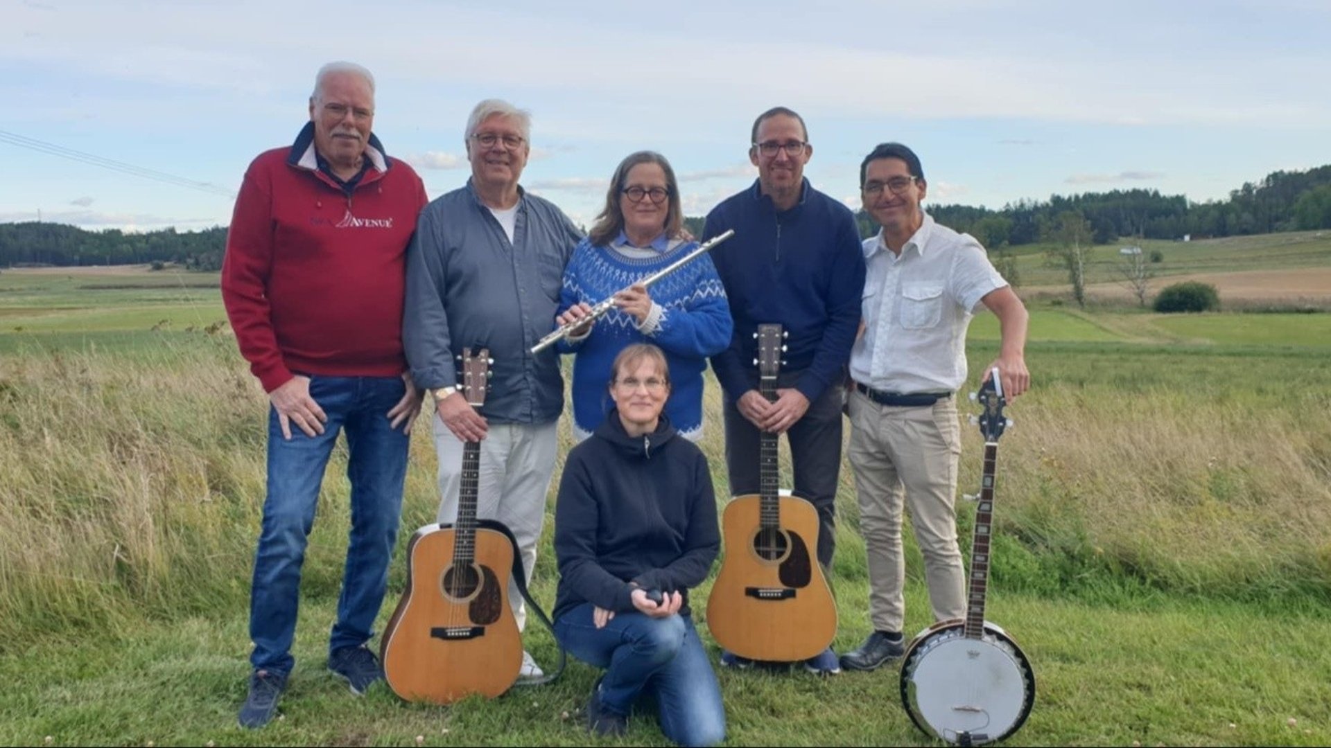 6 människor som står med instrument på ett fält