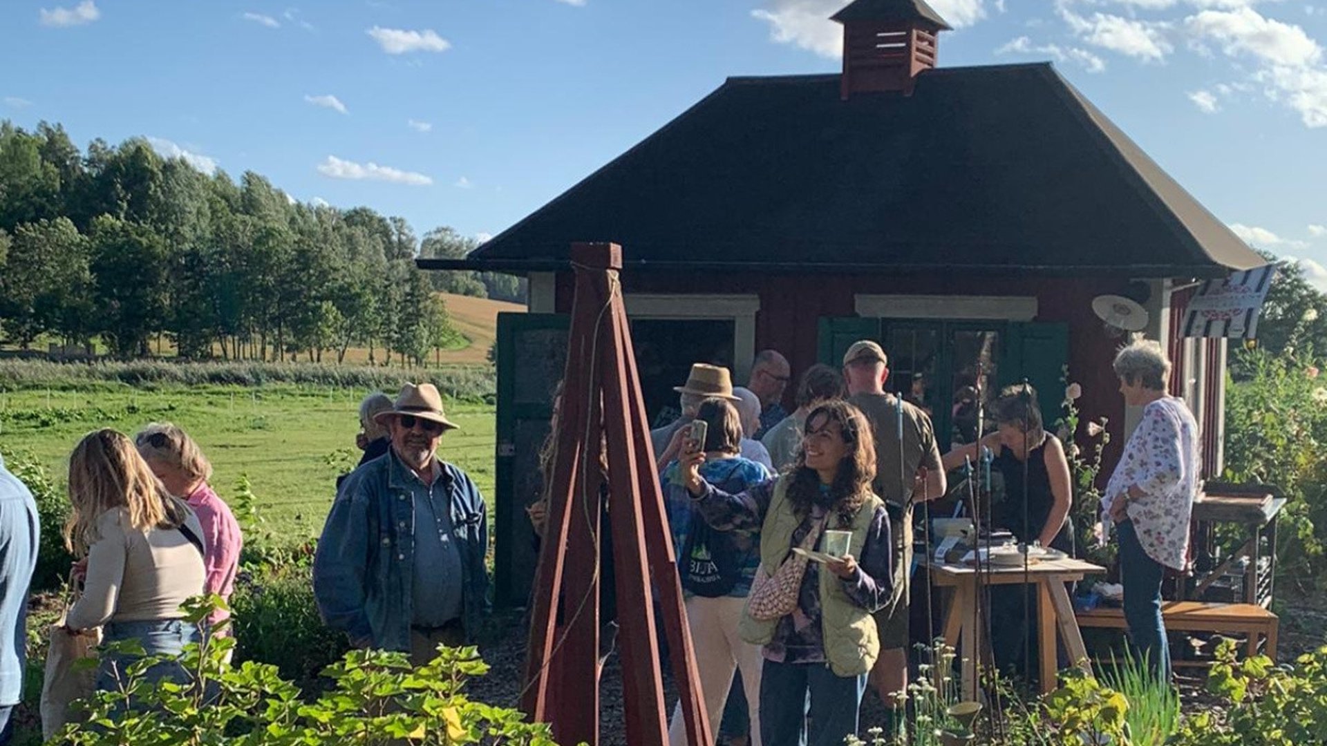 Många besökare utanför en liten gårdsbutik på landsbygden. 