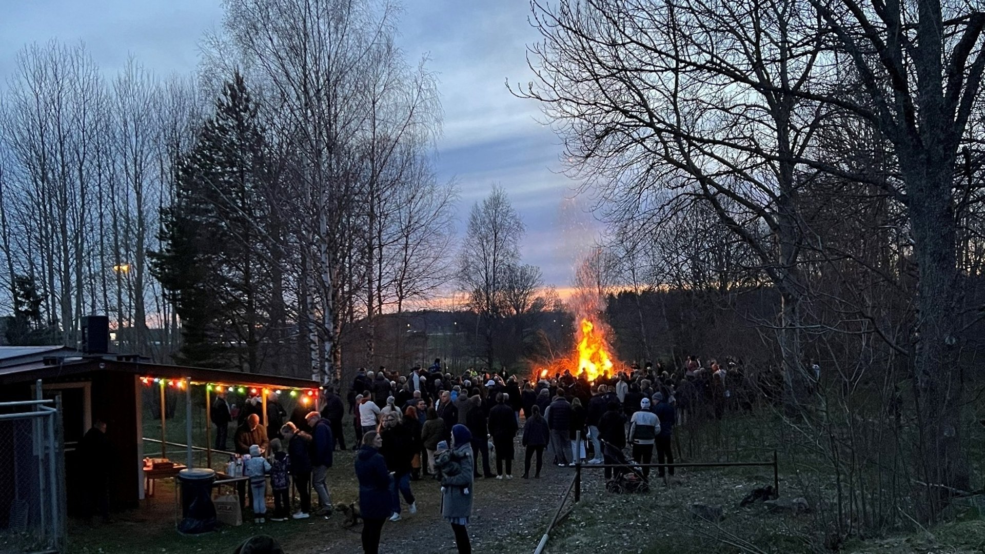 Människor som står runt en valborgseld