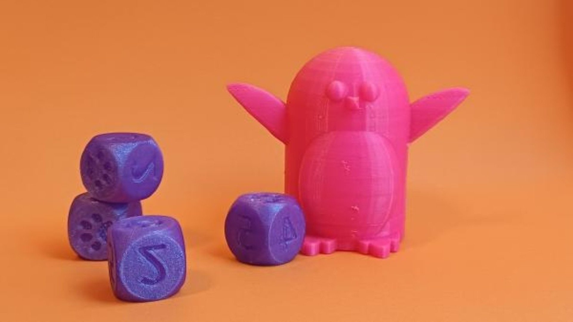 Tre 3D-printade tärningar och en rosa pingvin.