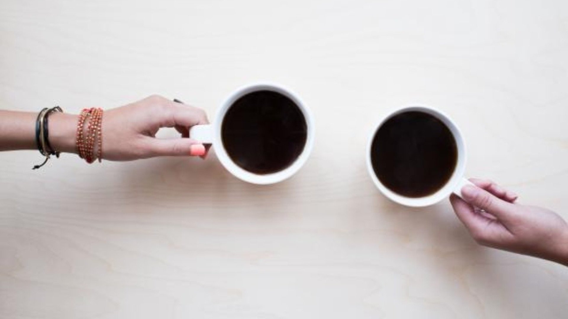 Två personer skålar med varsin kaffekopp.