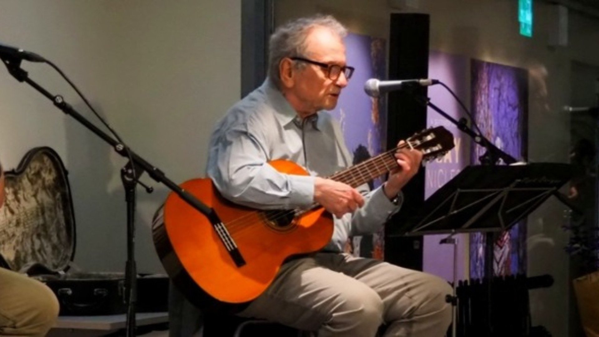 Tore sitter framför en mikrofon o spelar gitarr