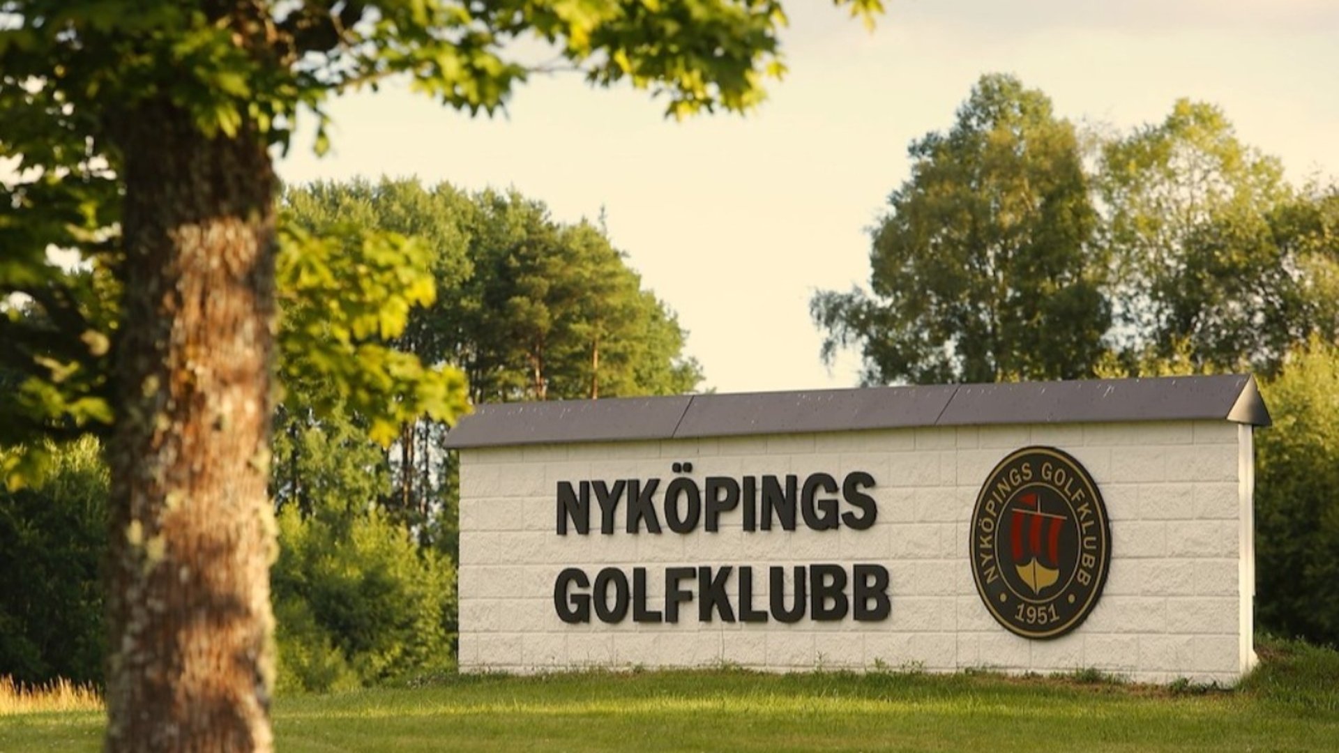 Golfklubbens skylt med logotyp i grönskande natur