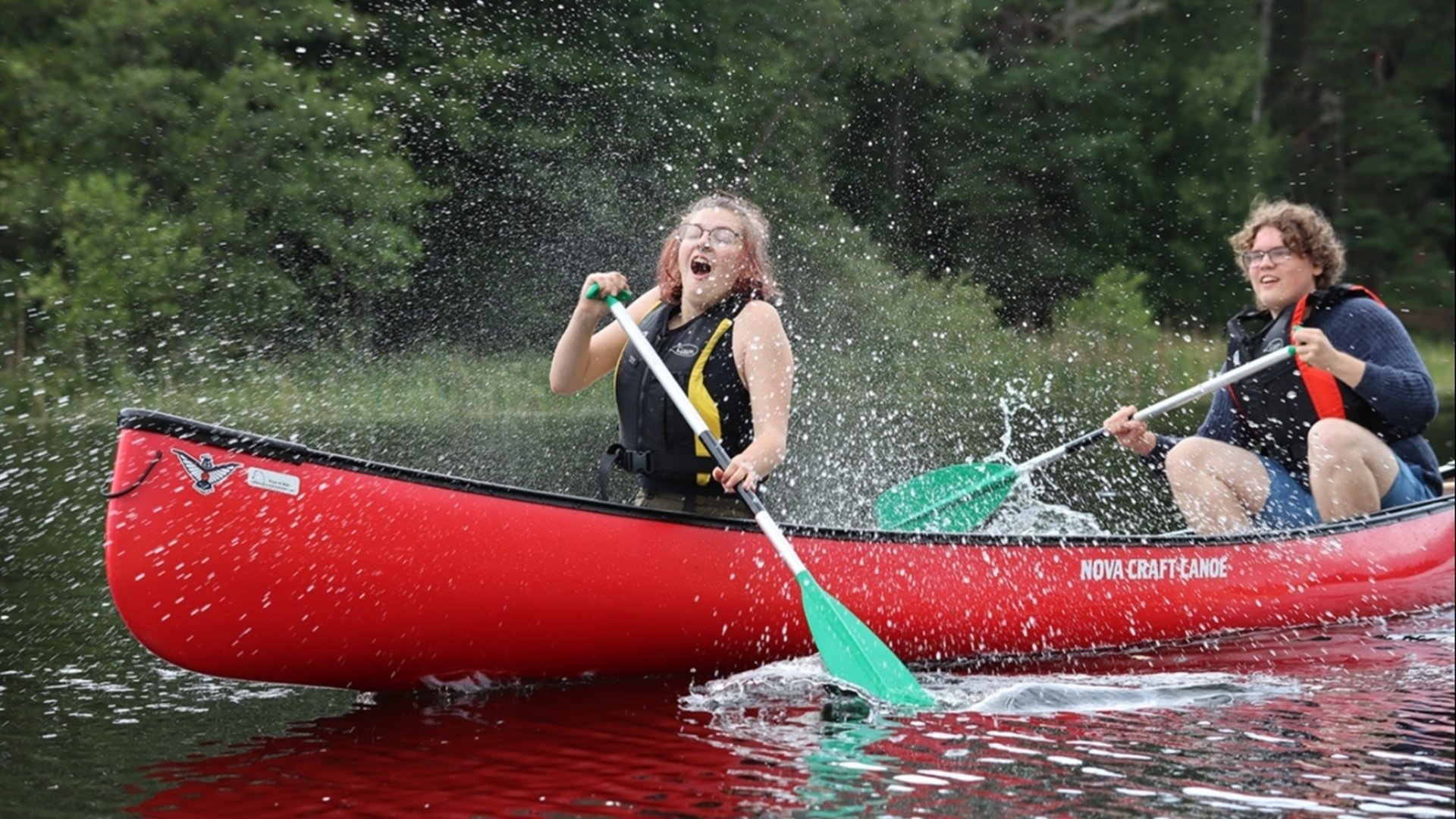 Två ungdomar i en röd kanot