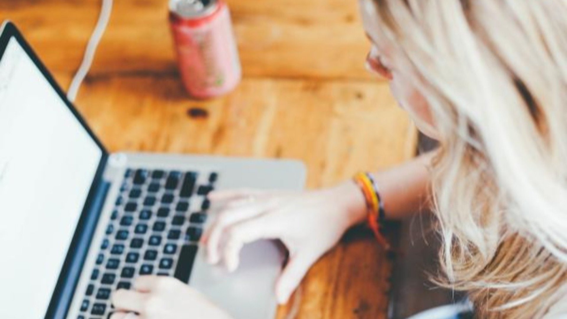 EN blond kvinna sitter framför en laptop och ser ut att jobba.