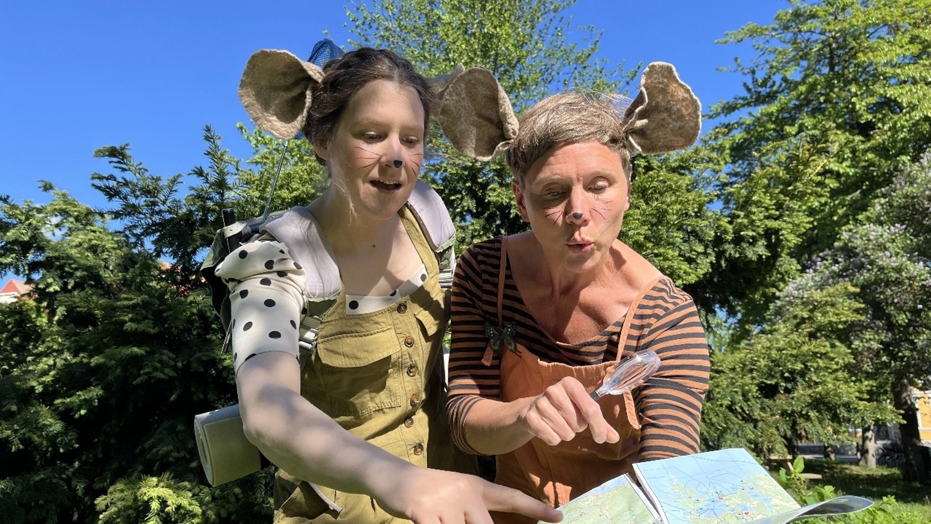 Två människor utklädda till möss följer en karta.