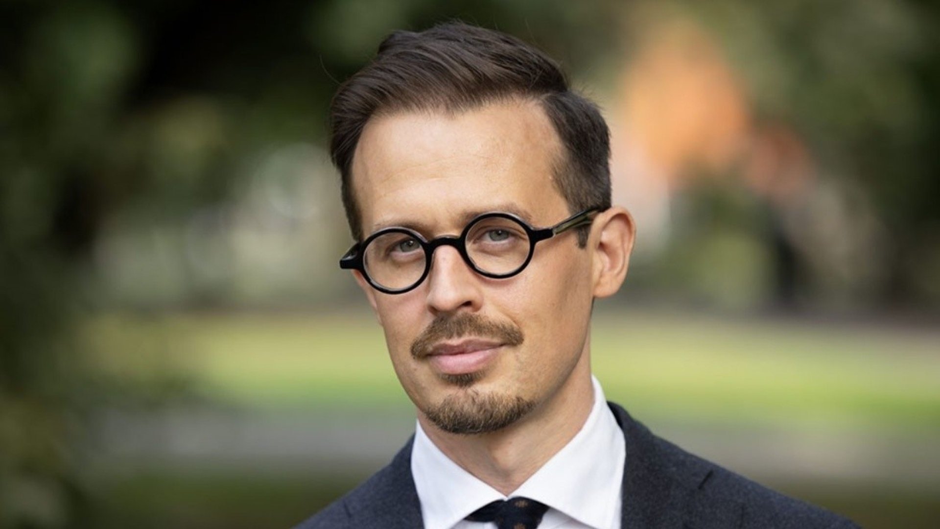 En man med glasögon och mustasch. 