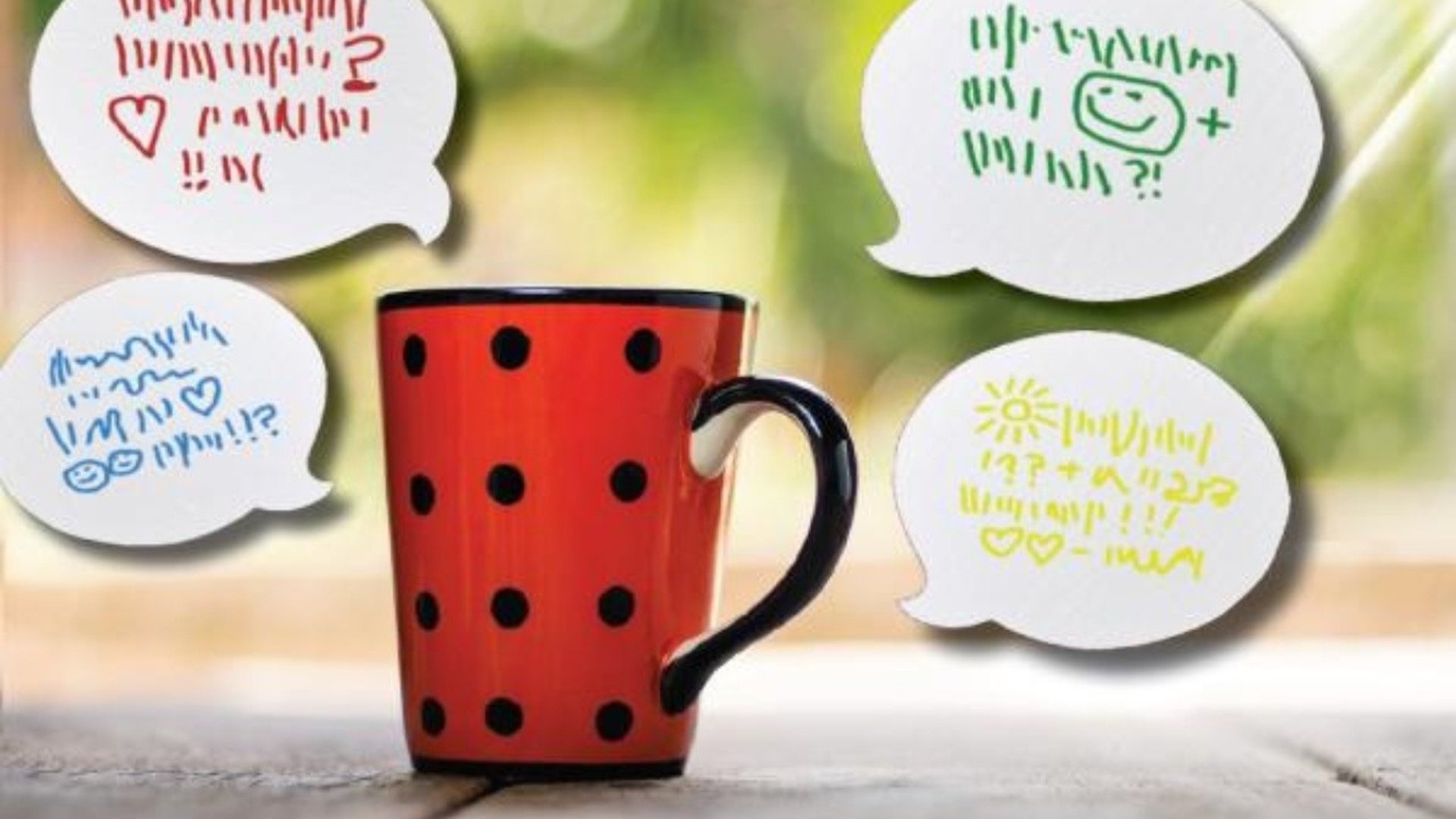 Röd prickig kaffemugg med talbubblor med påhittade språk i.