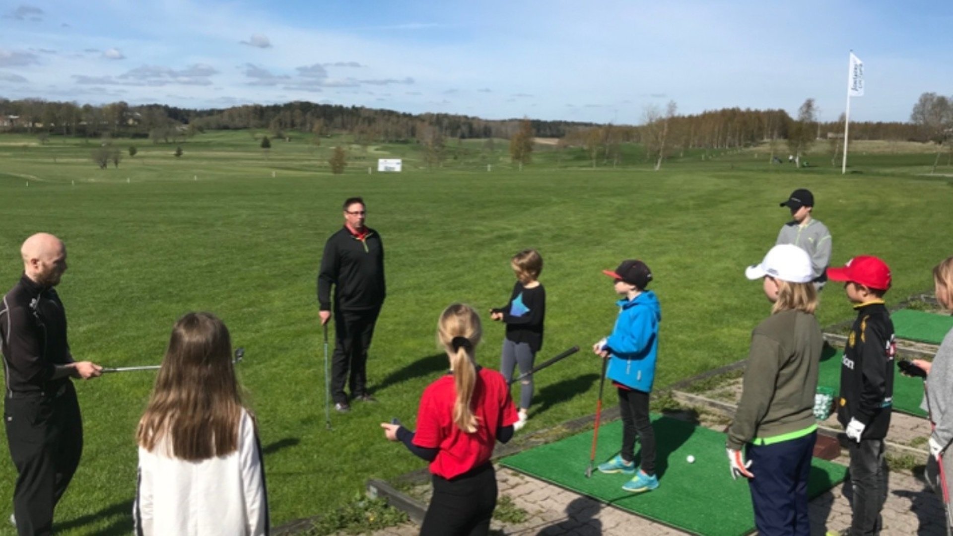 Barn och vuxna som står på en golfbana