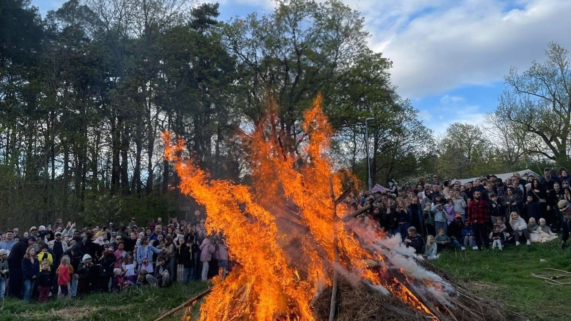 Fåfängans valborgseld i förgrunden, en stor grupp människor bildar fond i bakgrunden.