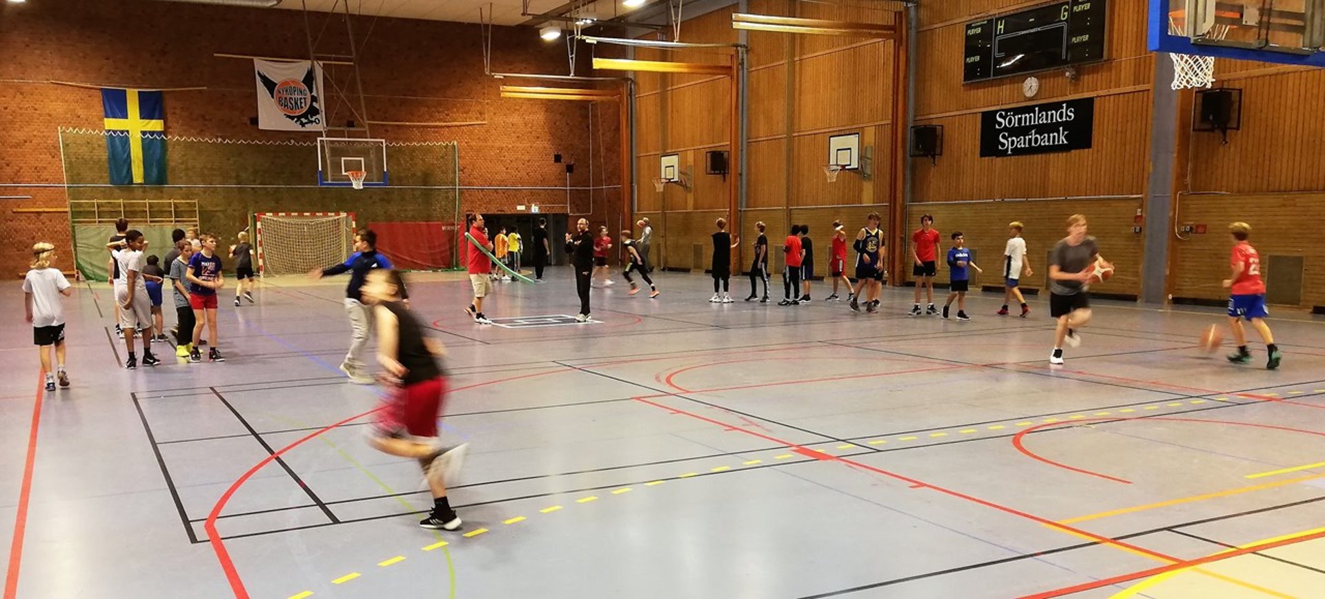 Flera barn i Sporthallen som spelar basket.