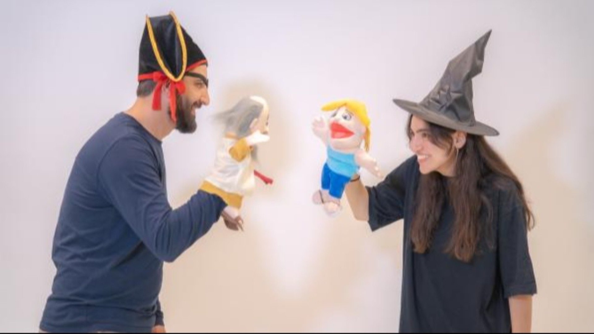 Två skådespelare, en man och en kvinna, står med varsin handdocka.