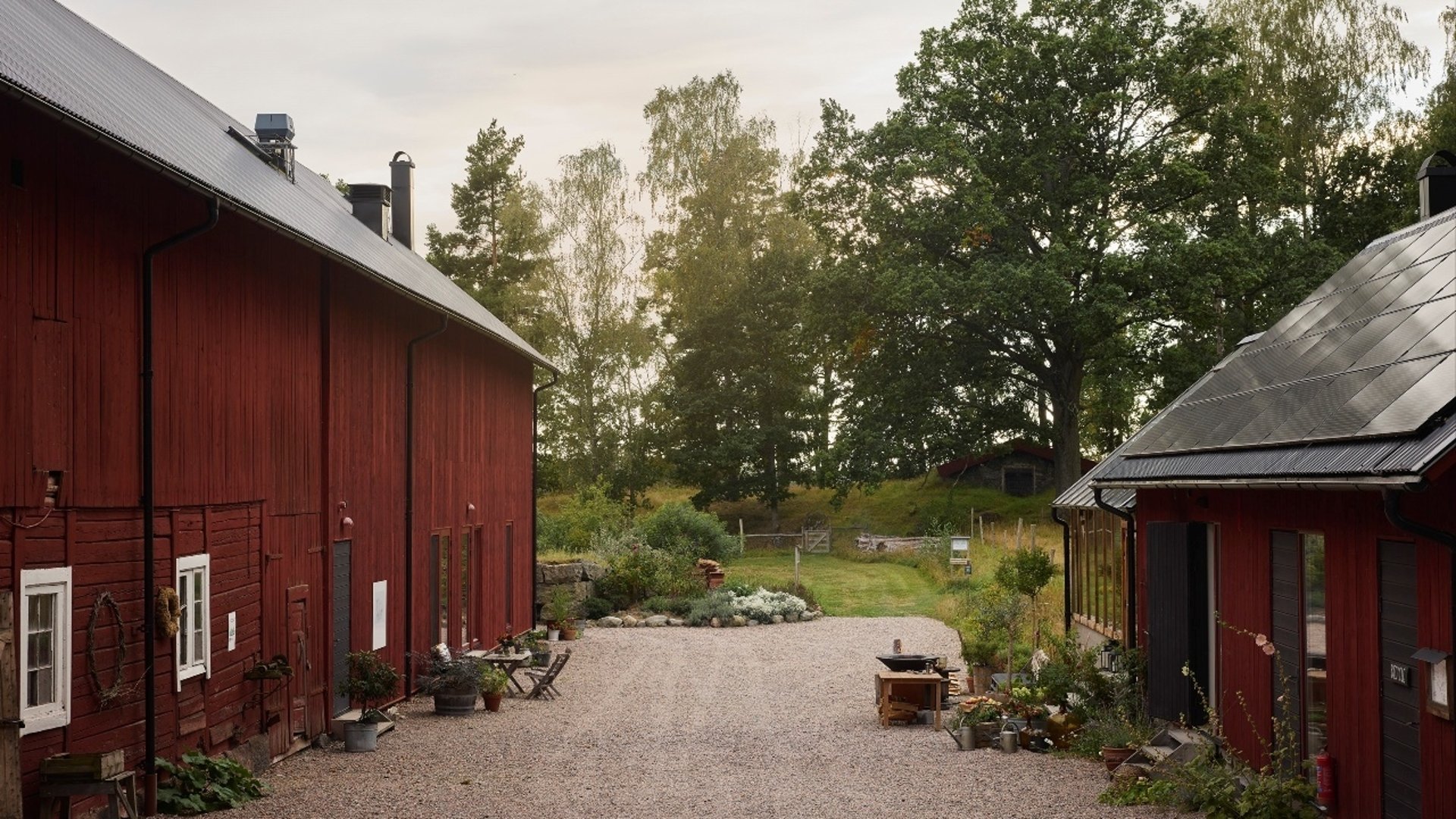 En röd ladugård och ett rött hus vid en gårdsplan.