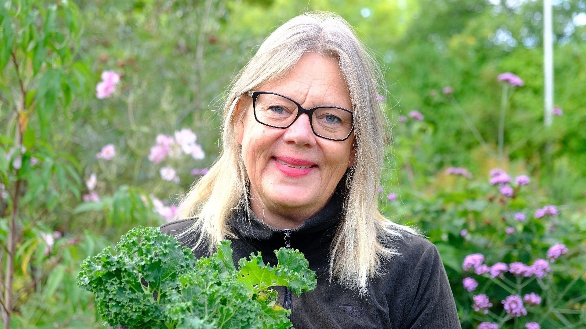 En glad kvinna i en trädgård