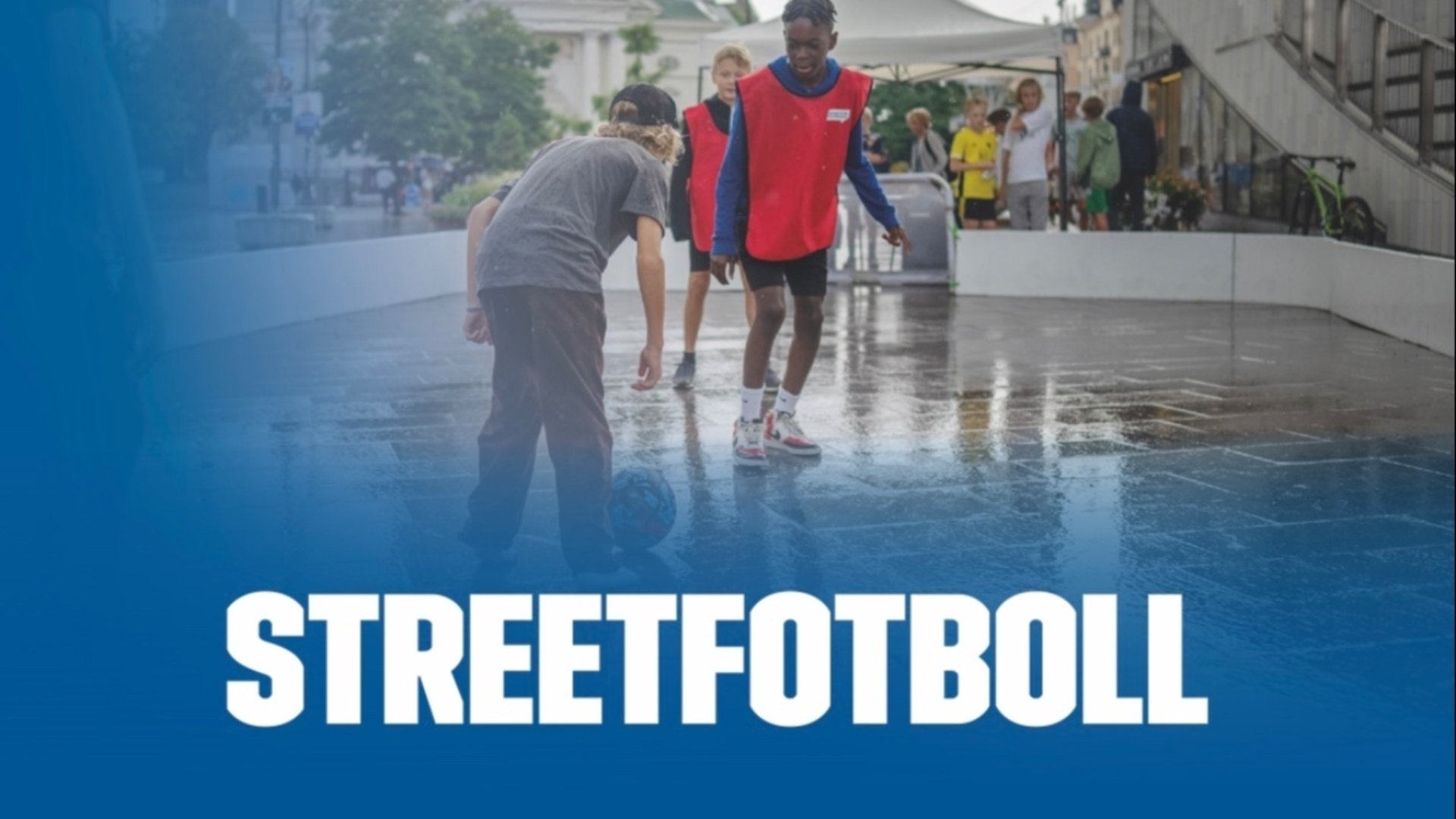 Barn som spelar fotboll inhägnat på asfalt med texten streetfotboll 