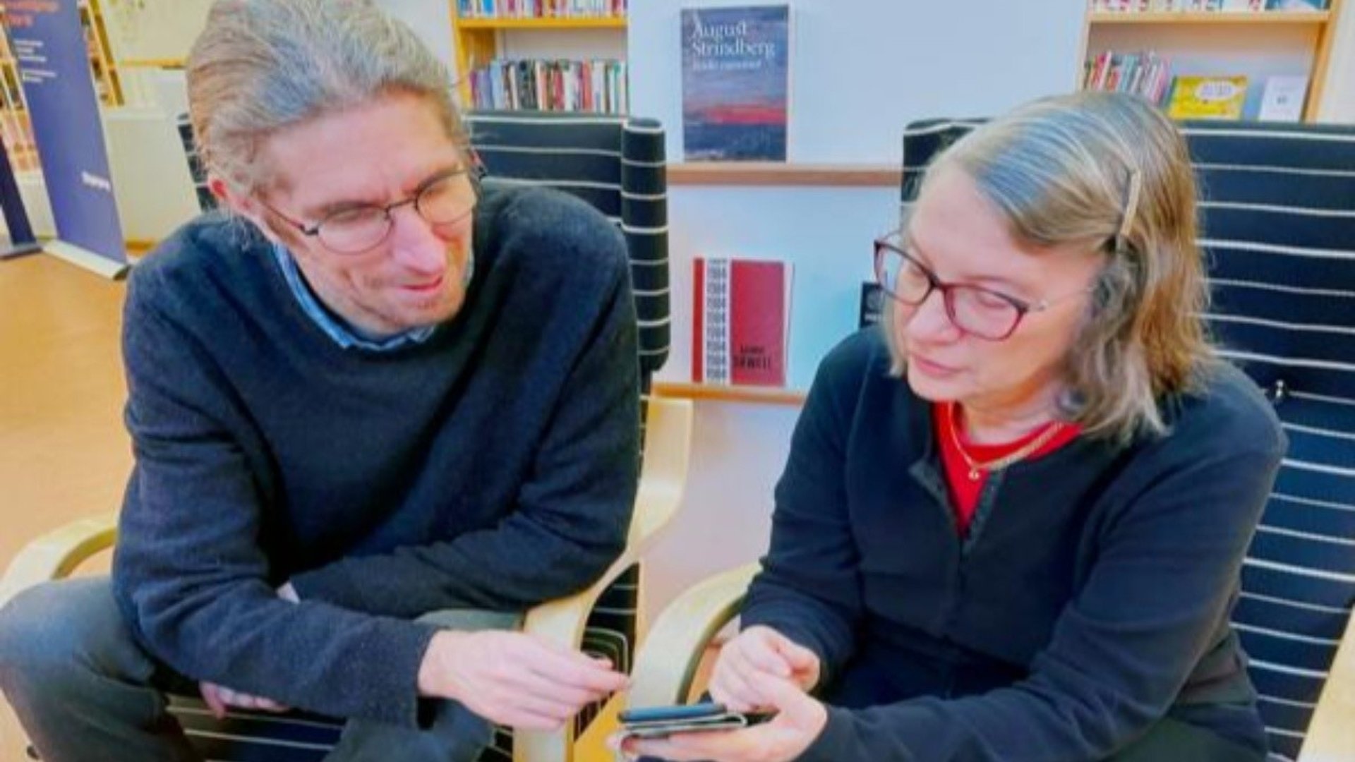 En äldre kvinna får hjälp med sin mobil.