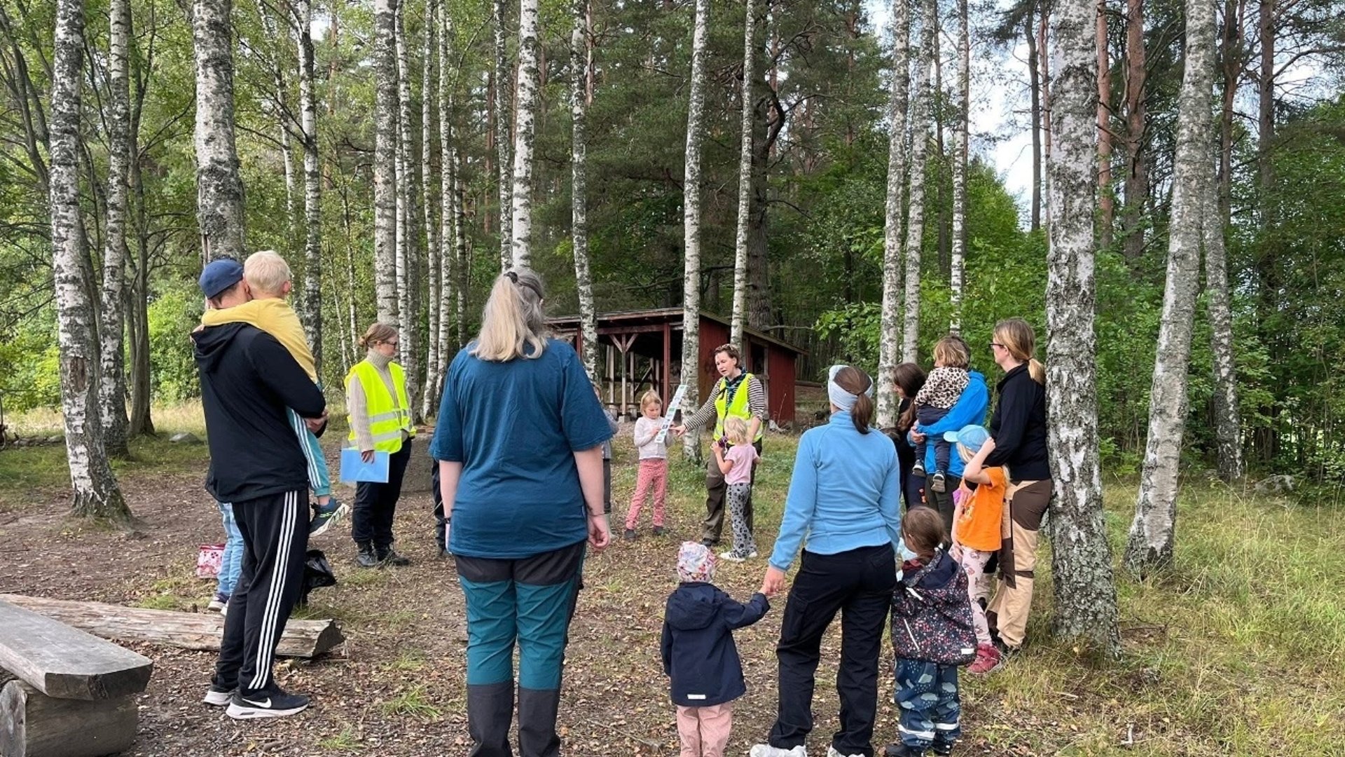 Bilden föreställer barn och vuxna som utomhus som är samlade i en cirkel.