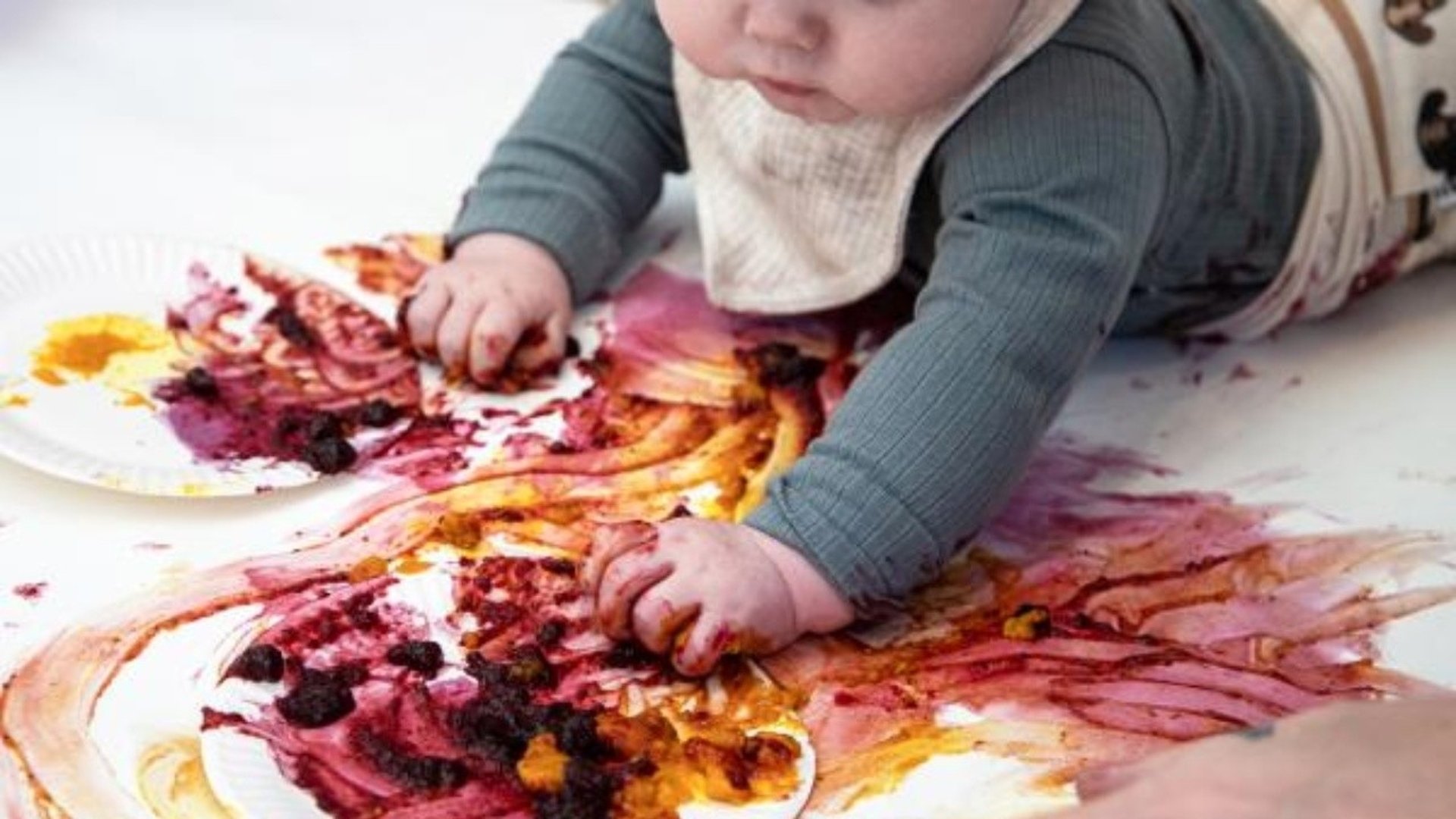 En bebis målar med fingrarna på golvet.