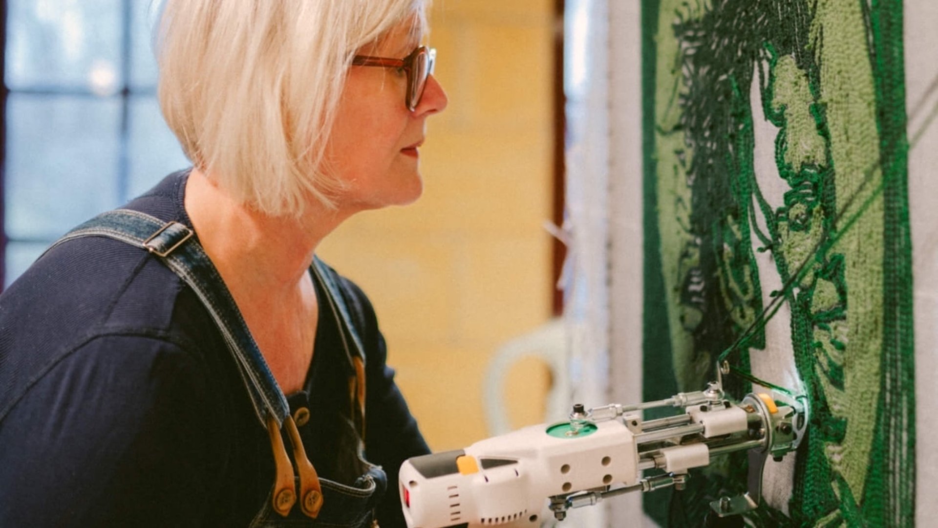 Marja tuftar ett porträtt med grönt ullgarn