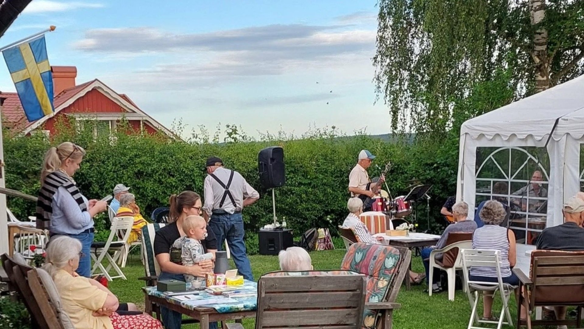 Sommarcafé med gamla och unga i somrig grönska