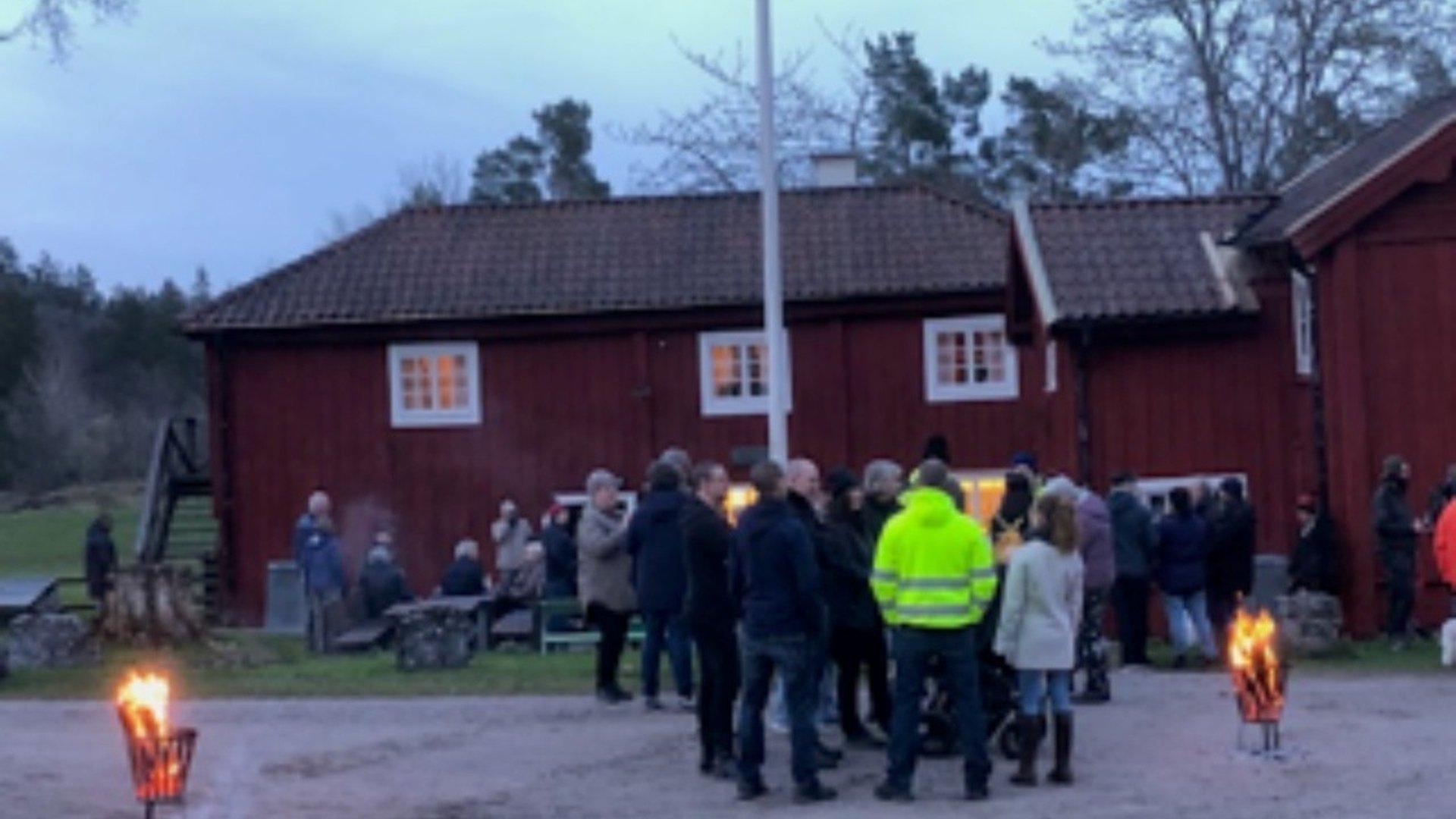 Människor som står runt ett rött hus
