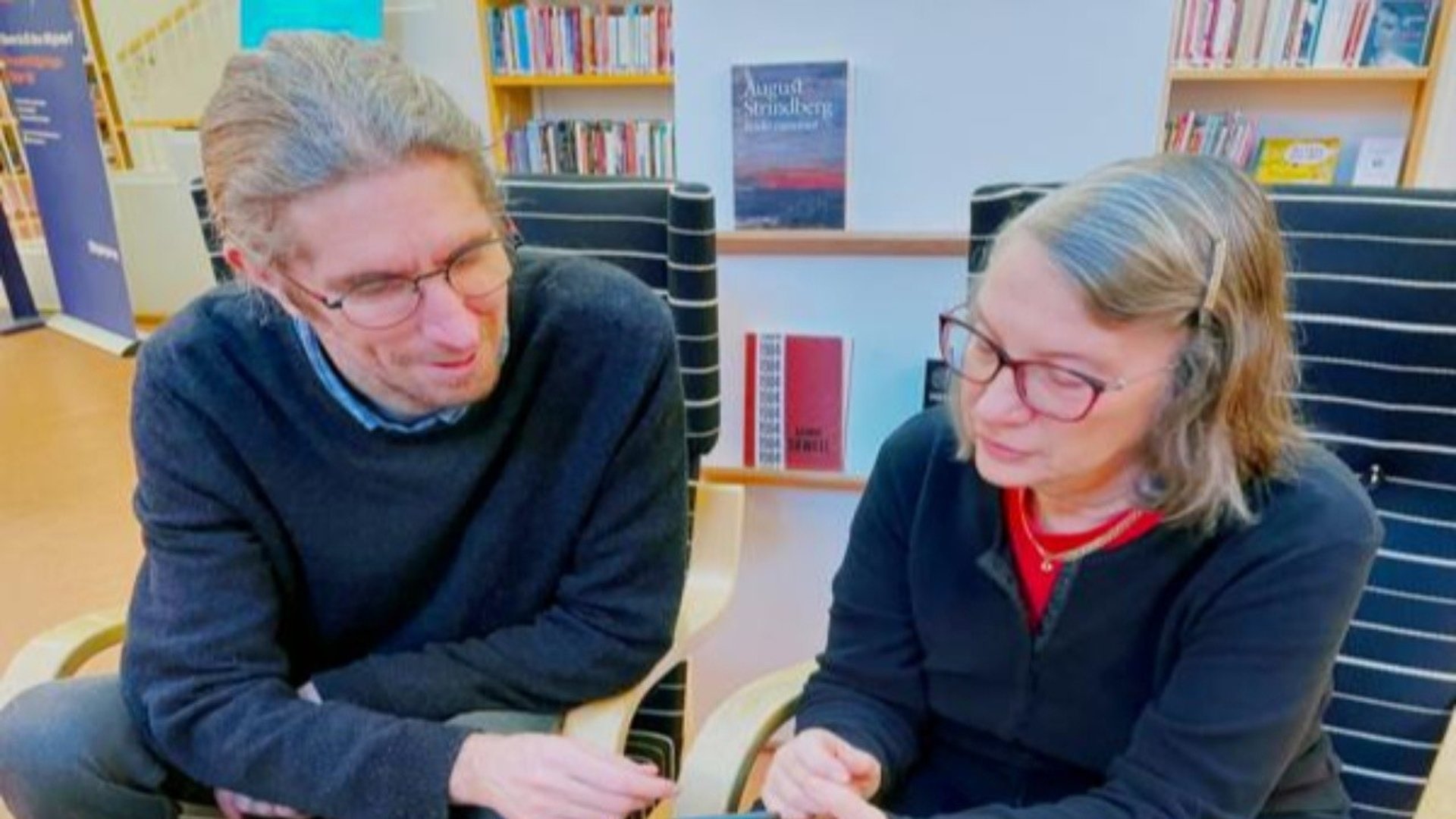 En bibliotekarie hjälper en besökare med hennes mobiltelefon.