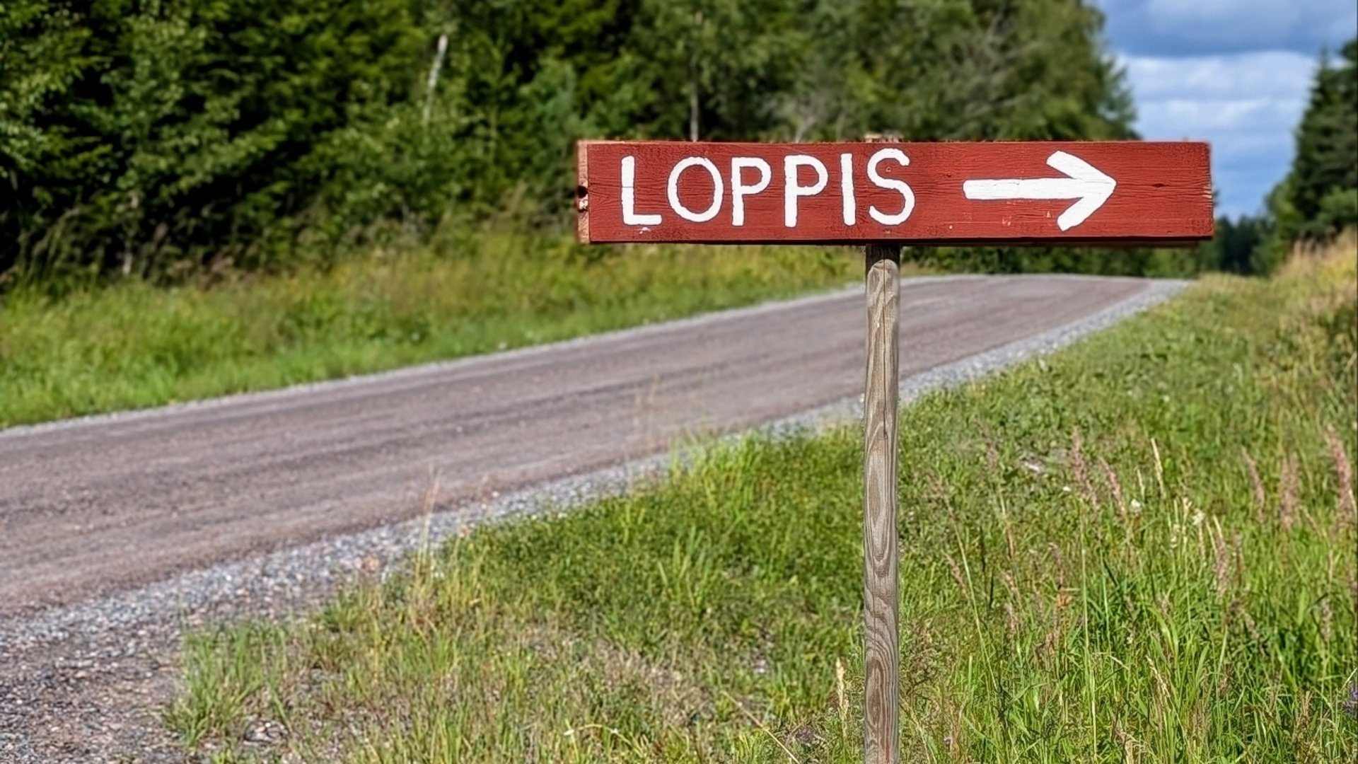 Skylt där det står loppis, placerad på sidan av en grusväg. 