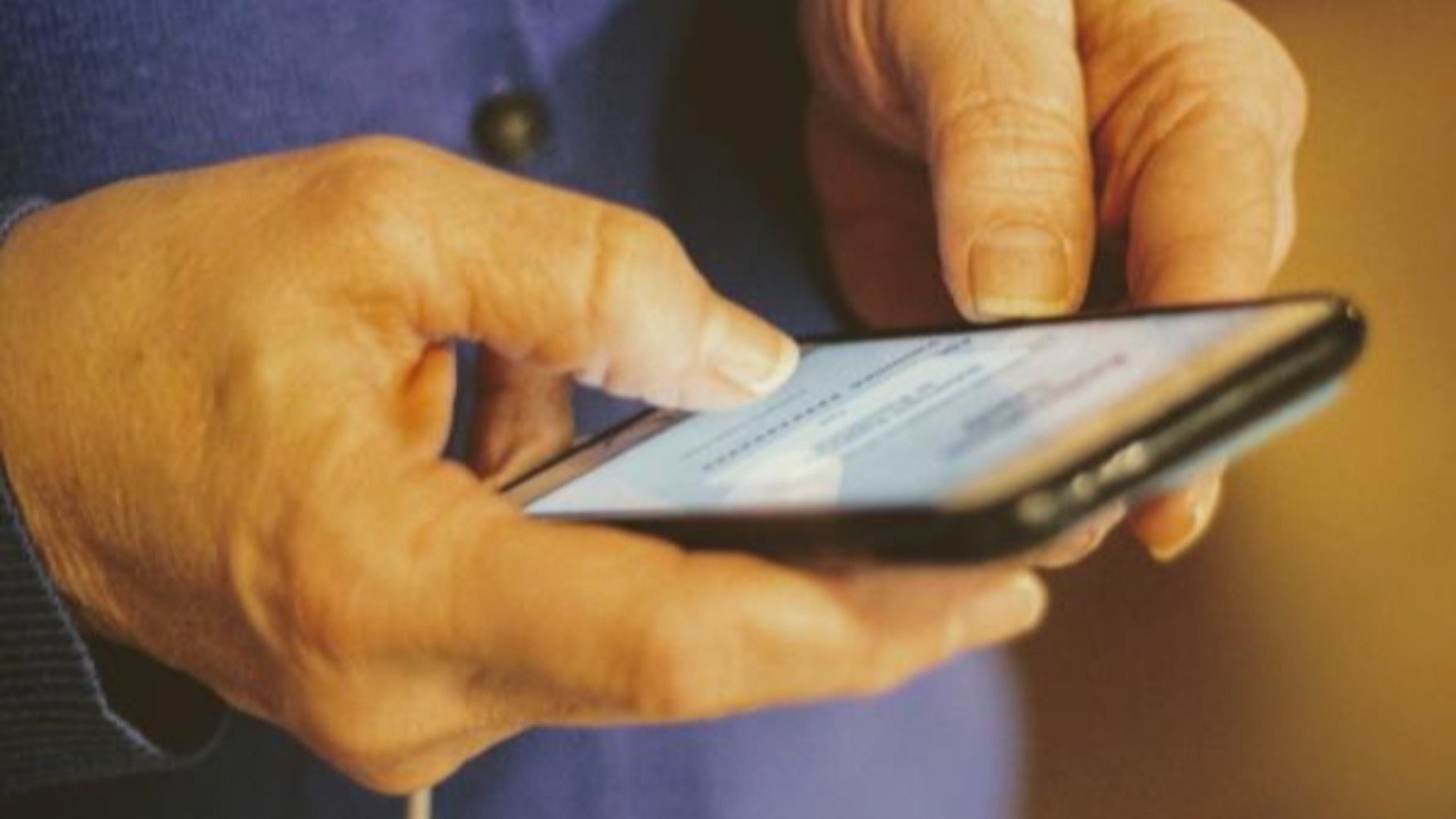 Man ser händerna på en person som håller i en mobiltelefon.
