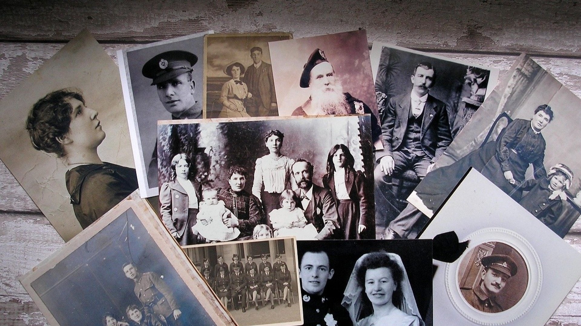 En mängd väldigt gamla fotografier utspridda på ett bord.