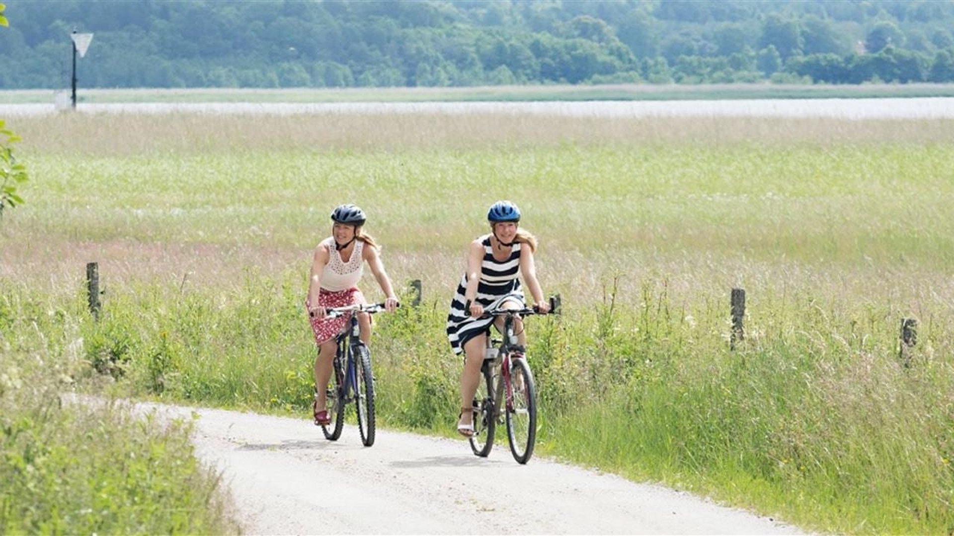 Två kvinnor cyklar längs en landsväg en sommardag