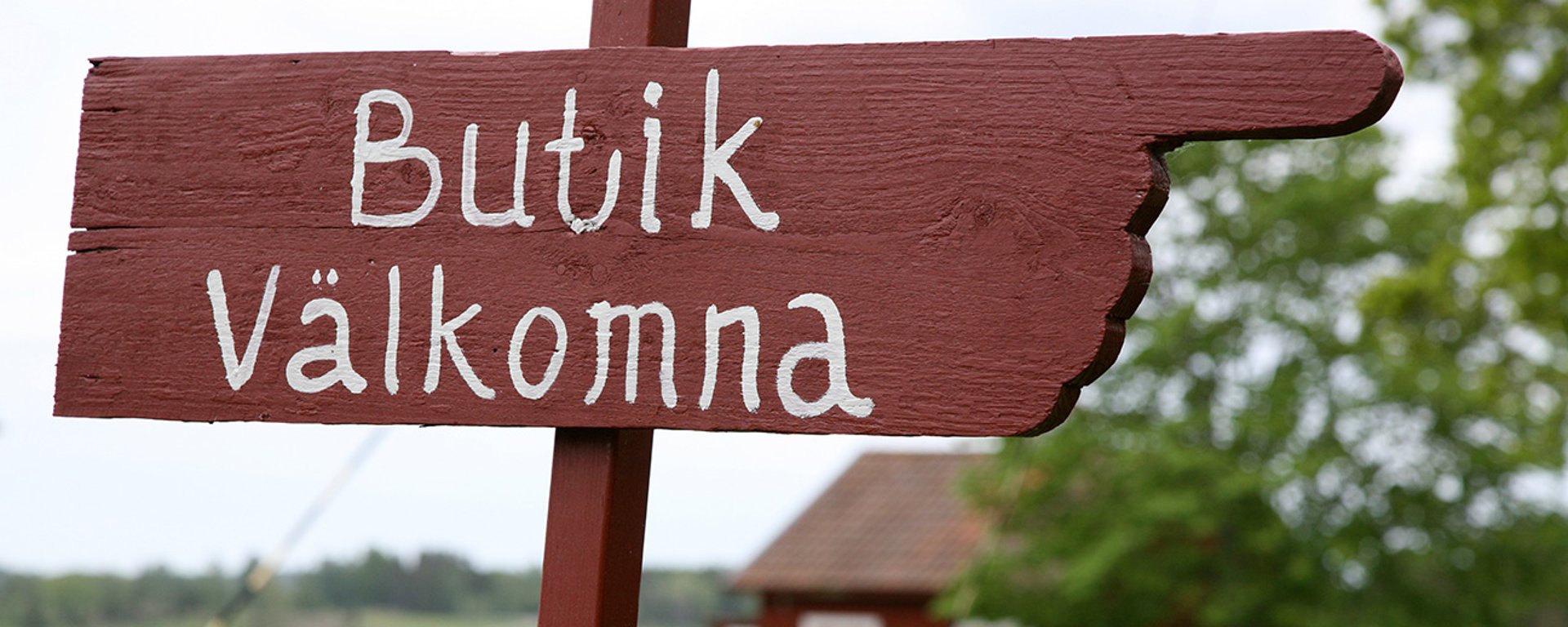 En rödmålad skylt hänvisar åt en butik.