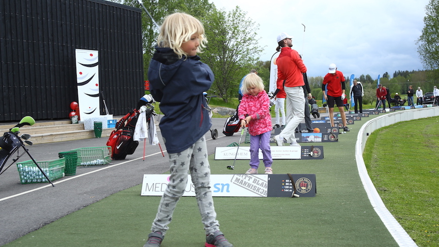 Barn som spelar golf på drivingrangen