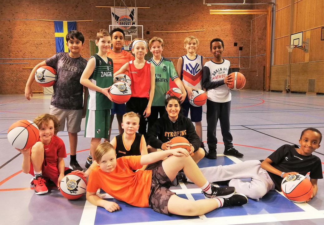 Flera som står och ligger och håller i basketbollar