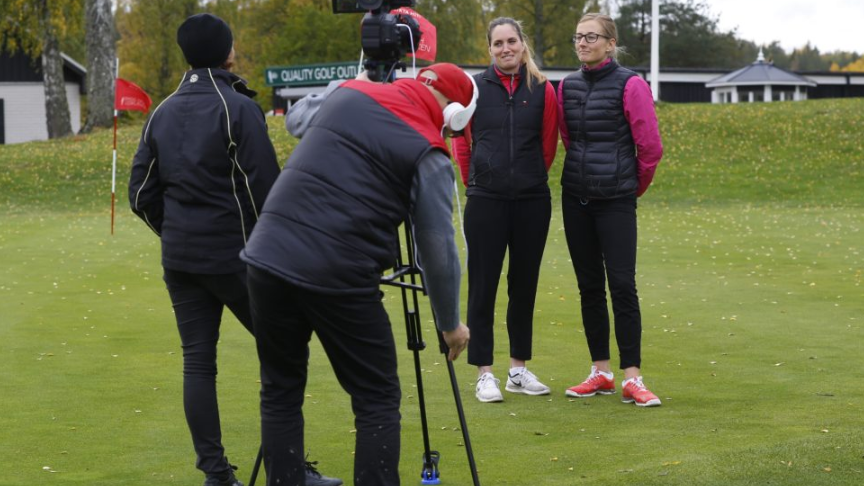 Två människor står och intervjuar två golfare