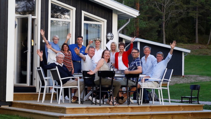Folk som sitter runt ett bord med händerna i luften