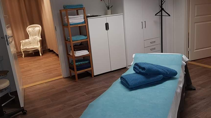 Ett spa rum med en säng och dörren öppen till väntrummet